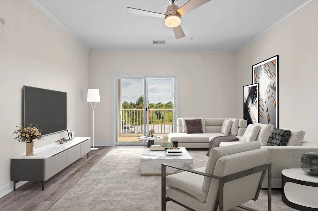 Bright modern living room with light gray sectional sofa, armchair, marble coffee table, TV on low console, and sliding glass door opening to balcony.