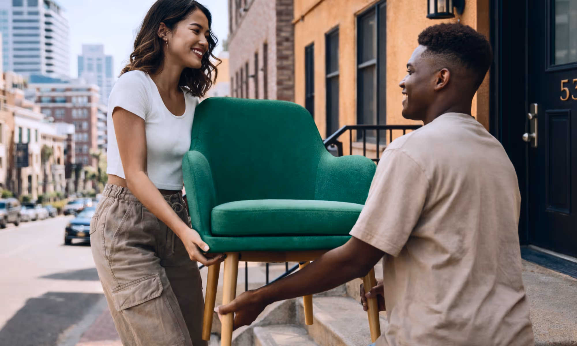 A young man and young woman exchanging a green chair