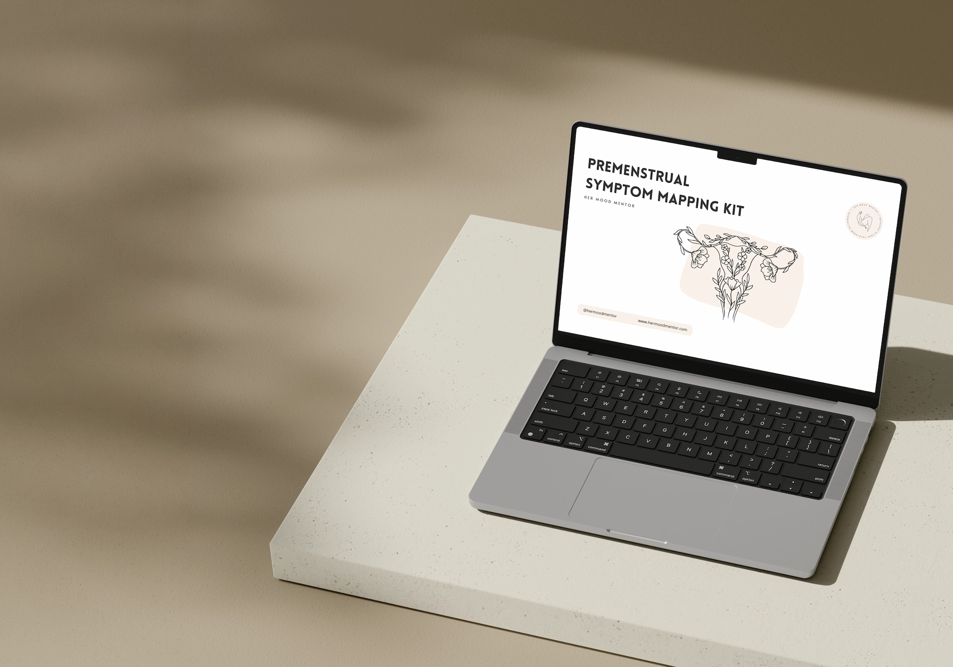 Laptop on a beige surface displaying a webpage titled 'Premenstrual Symptom Mapping Kit' with a floral illustration of a uterus.