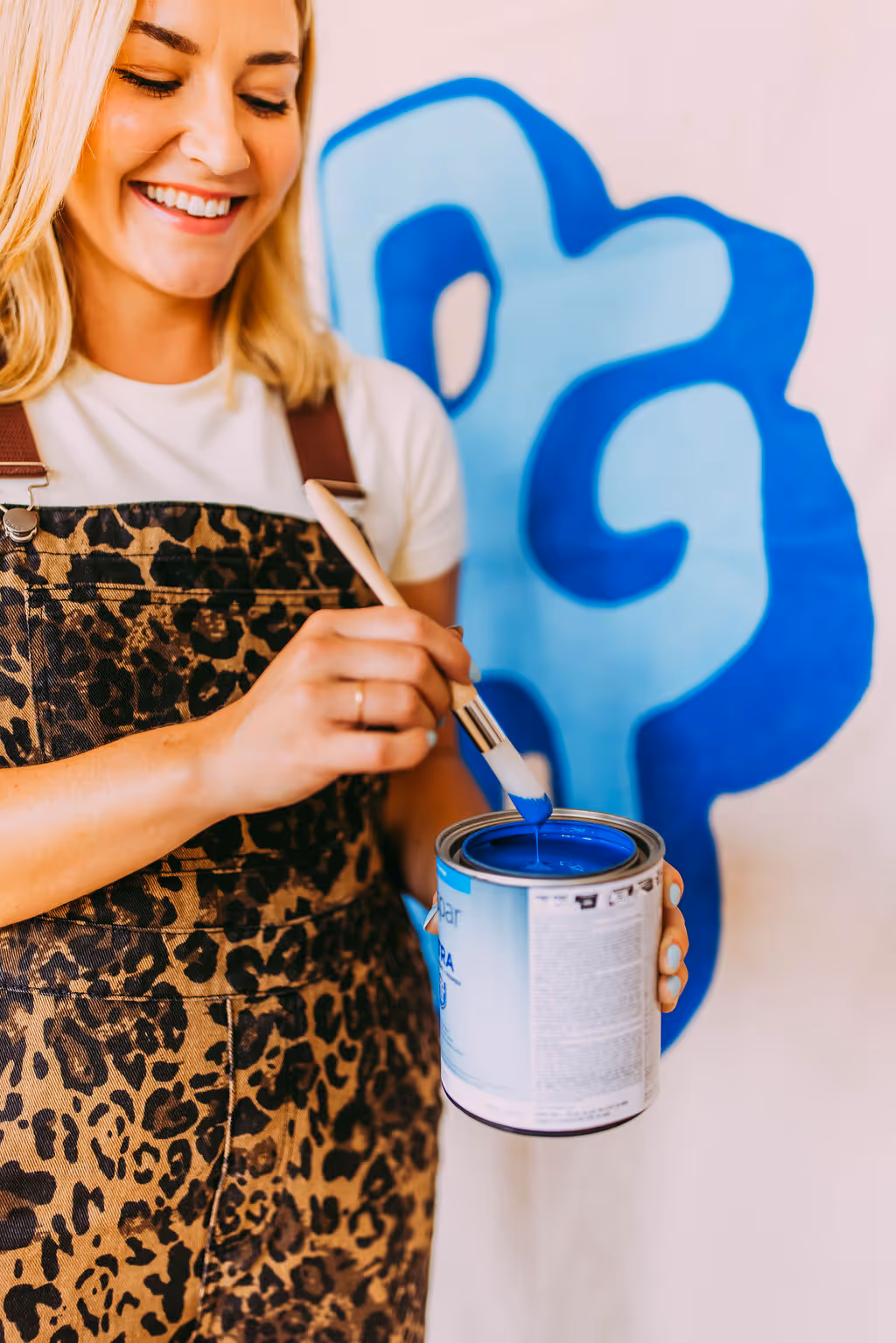 A woman painting a mural with blue paint