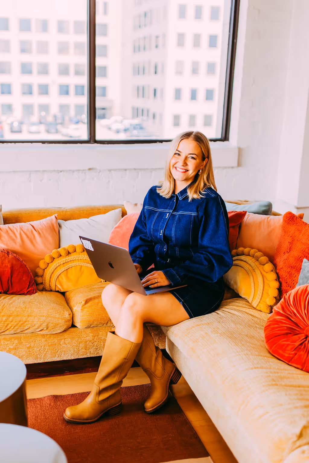 A graphic designer sitting with her laptop on a couch
