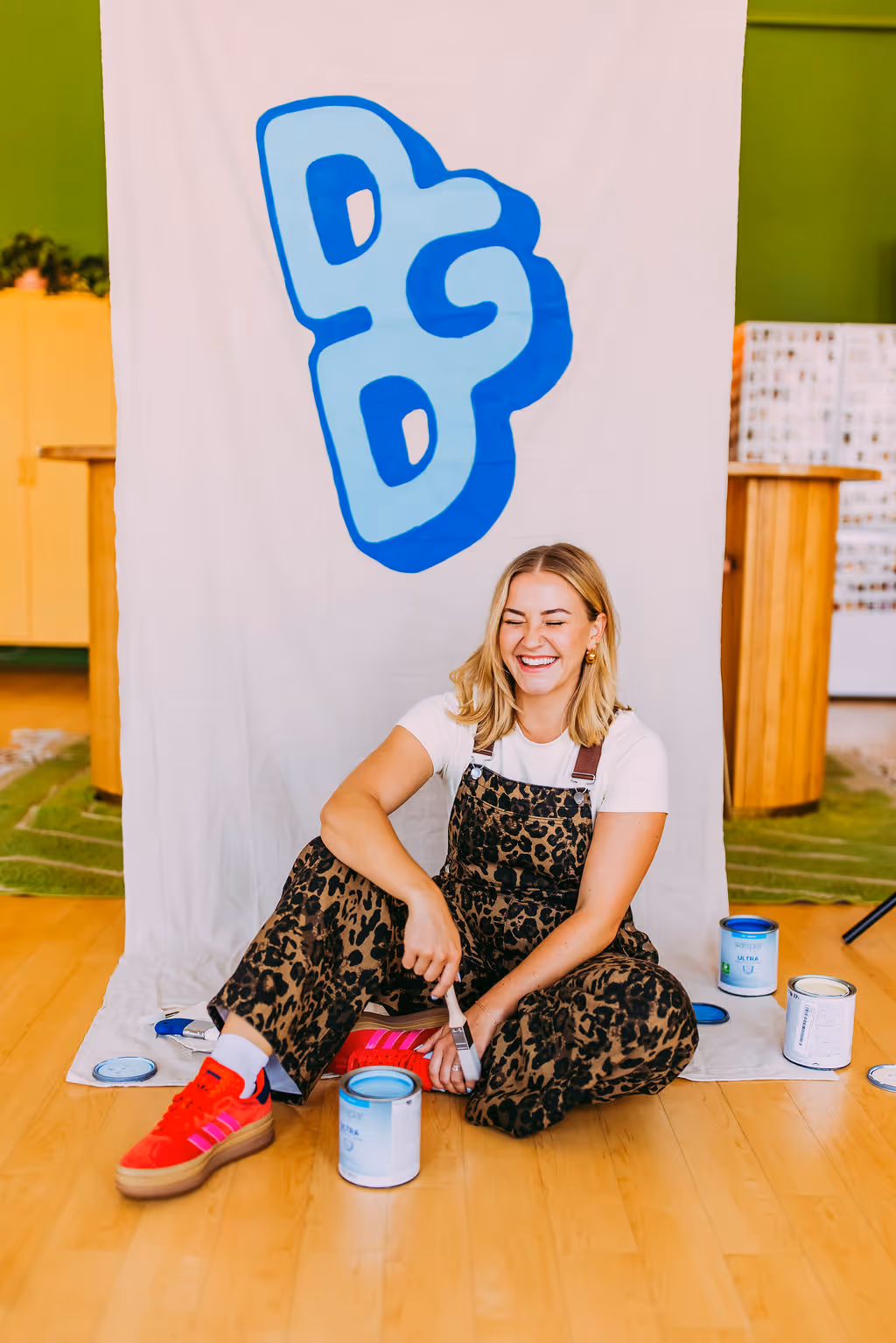 An artist sitting down next to a hand painted mural