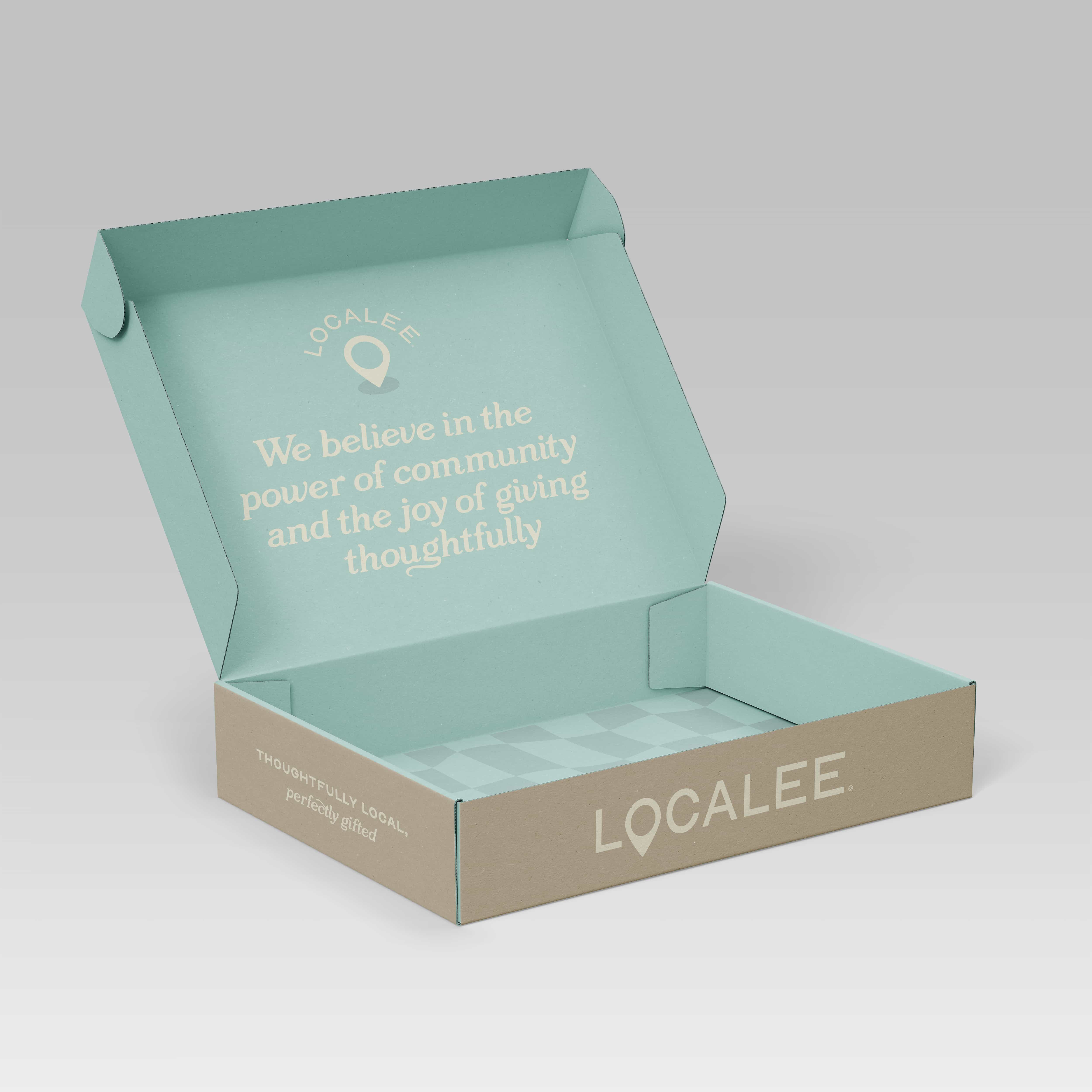 Open pastel green and tan gift box with text on the inside lid reading 'We believe in the power of community and the joy of giving thoughtfully' and the brand name 'Localee' on the front side.