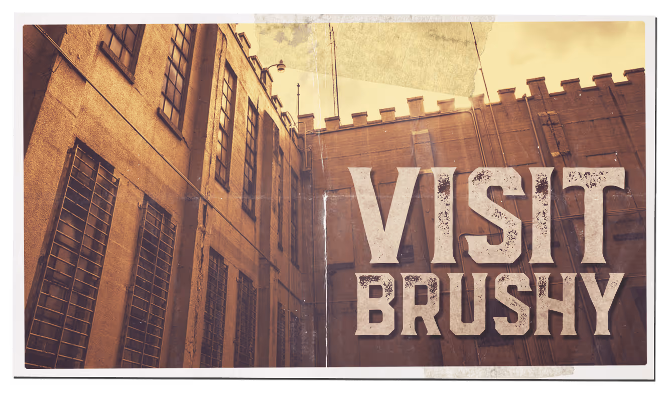 Vintage-style photo of a brick prison building with barred windows and text saying 'Visit Brushy'.