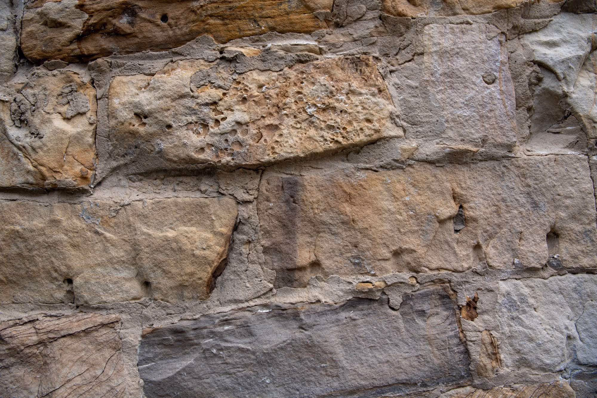 Close-up of a weathered stone wall with irregularly shaped stones and visible mortar.