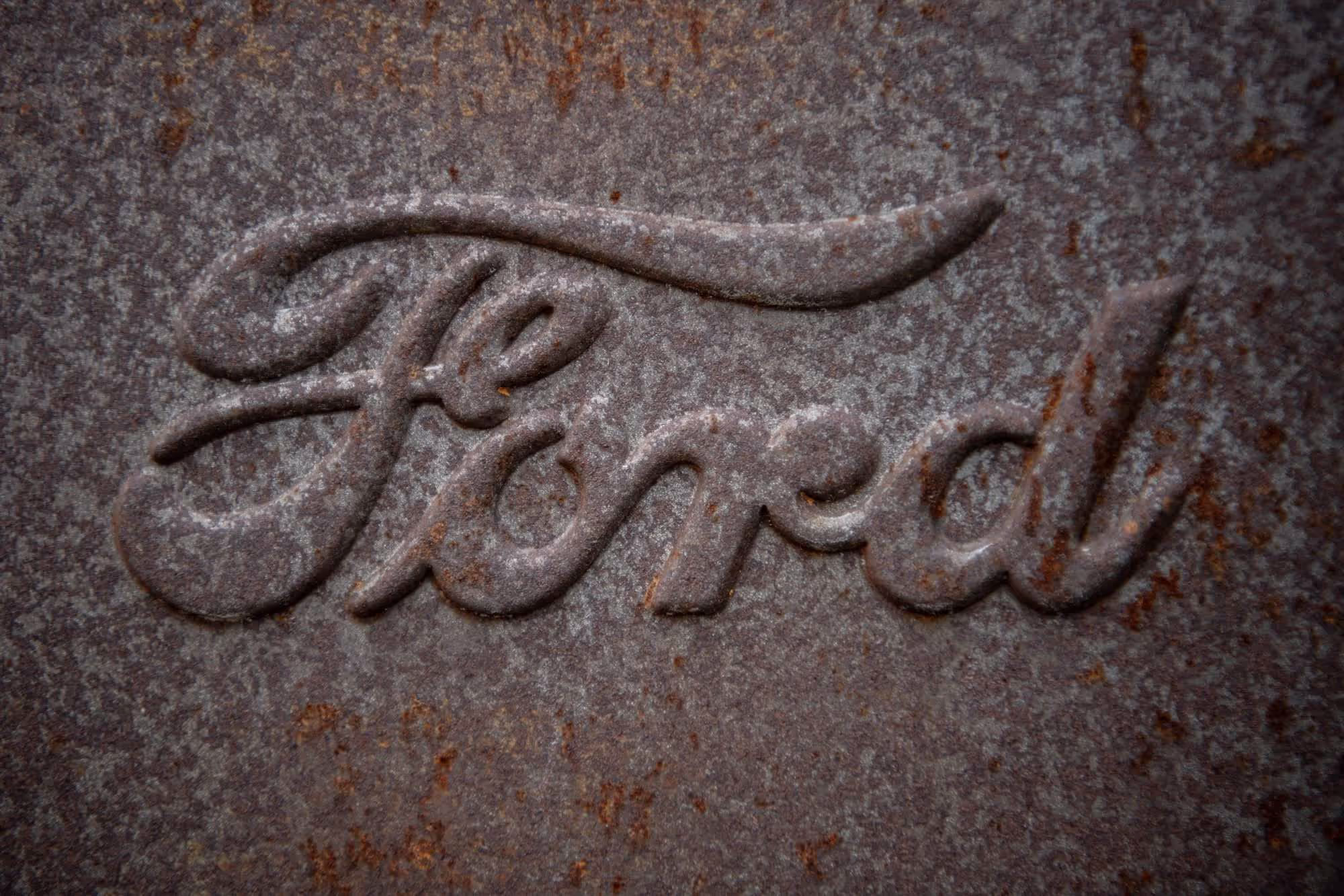 Rusted Ford logo embossed on a metal surface.