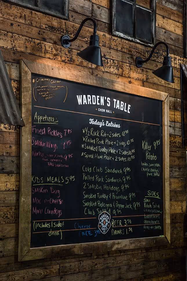 Wood-framed chalkboard menu at Warden's Table restaurant listing appetizers, kid's meals, today's entrées, sides, and drinks.