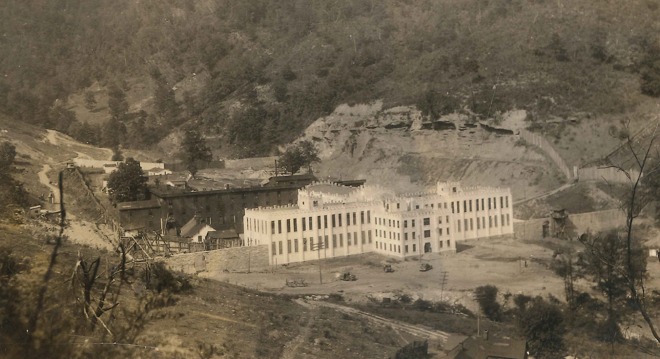 Black and white historical aerial photo of the large Brushy Mountain Penitentiary surrounded by hills and sparse trees.