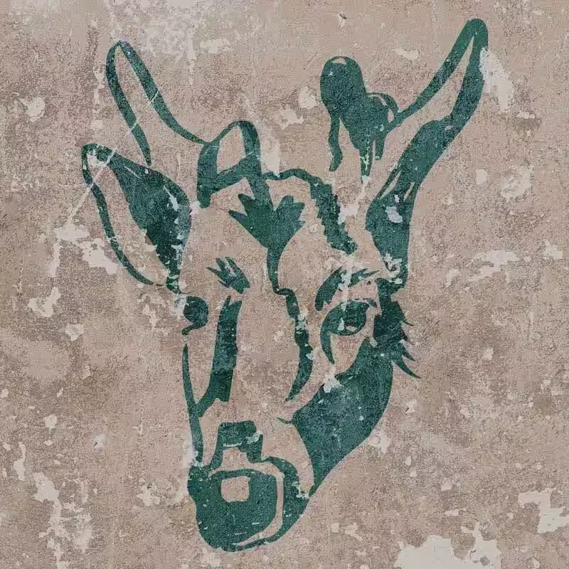 Weathered stencil art of the deer, Geronimo, face painted in dark green on a textured beige wall.