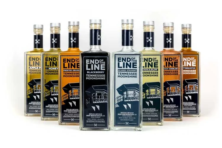 Eight bottles of End of the Line Tennessee Moonshine in various flavors including apple pie, honey, frosted orange, blackberry, scared straight, cinnarum, peach cobbler, and butterscotch.