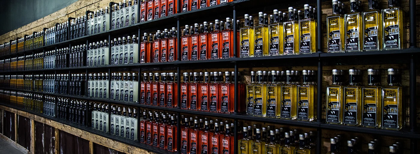 Shelves filled with rows of End of the Line Moonshine bottles in different flavors and colors.