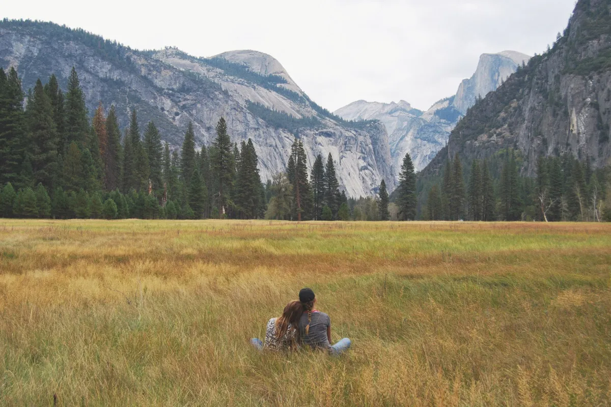 Couple sitting in grassy field in Yosemite