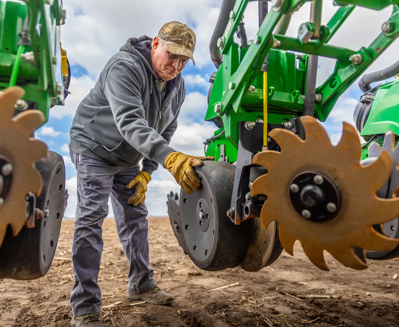 A farmer checks machinery for planting.