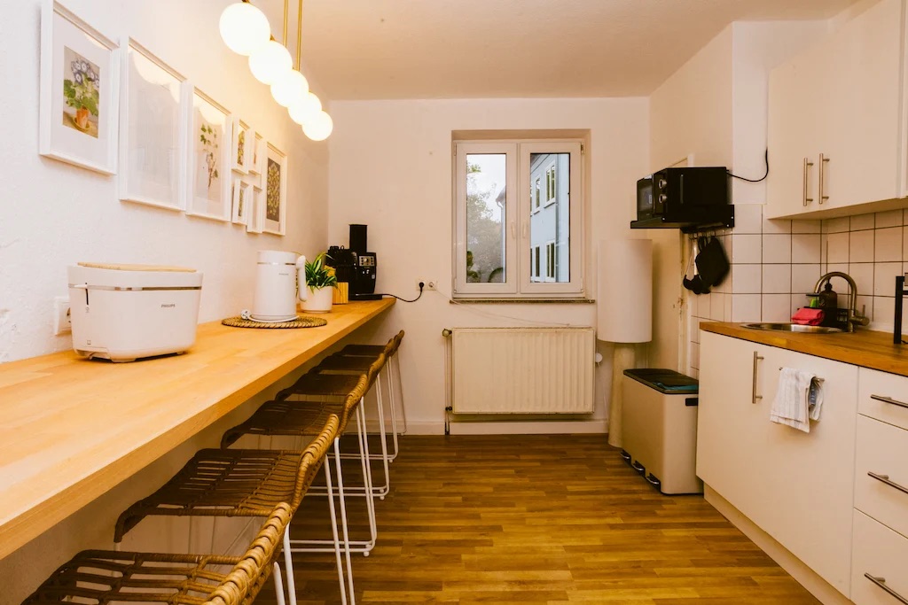 Helle Küchenzeile und Frühstückstheke mit Fensterblick in den Stadtpark Apartments Kassel