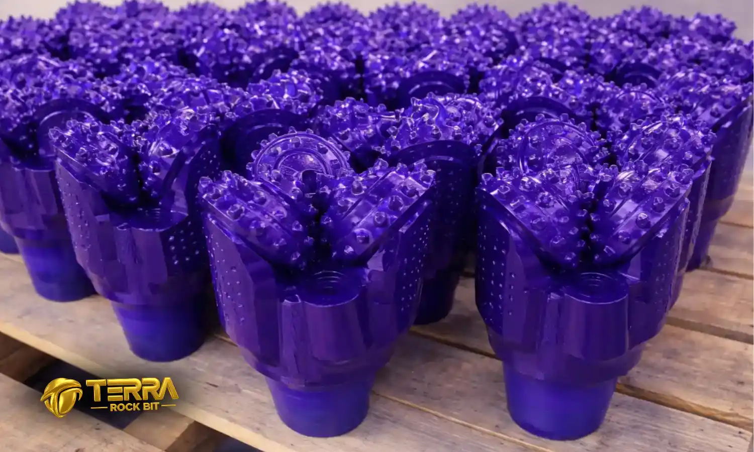 TERRA tricone drill bits in metallic purple finish stacked on pallet, premium HDD rock drilling tools