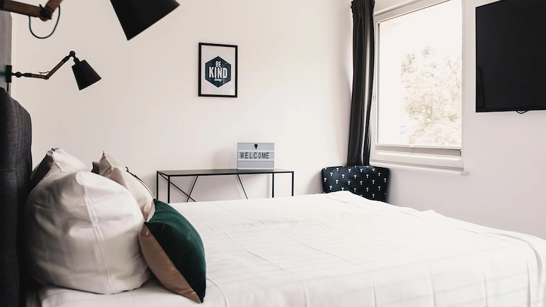 Zimmer Small mit Bett, Schreibtisch und Welcome-Schild im Boutiquehotel Palmenbad Kassel