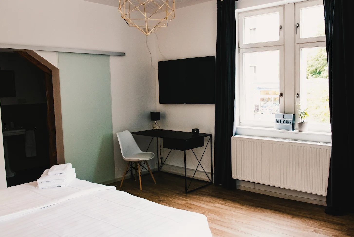 Zimmer Small mit Schreibtisch, TV und Gold-Pendelleuchte im Boutiquehotel Palmenbad Kassel