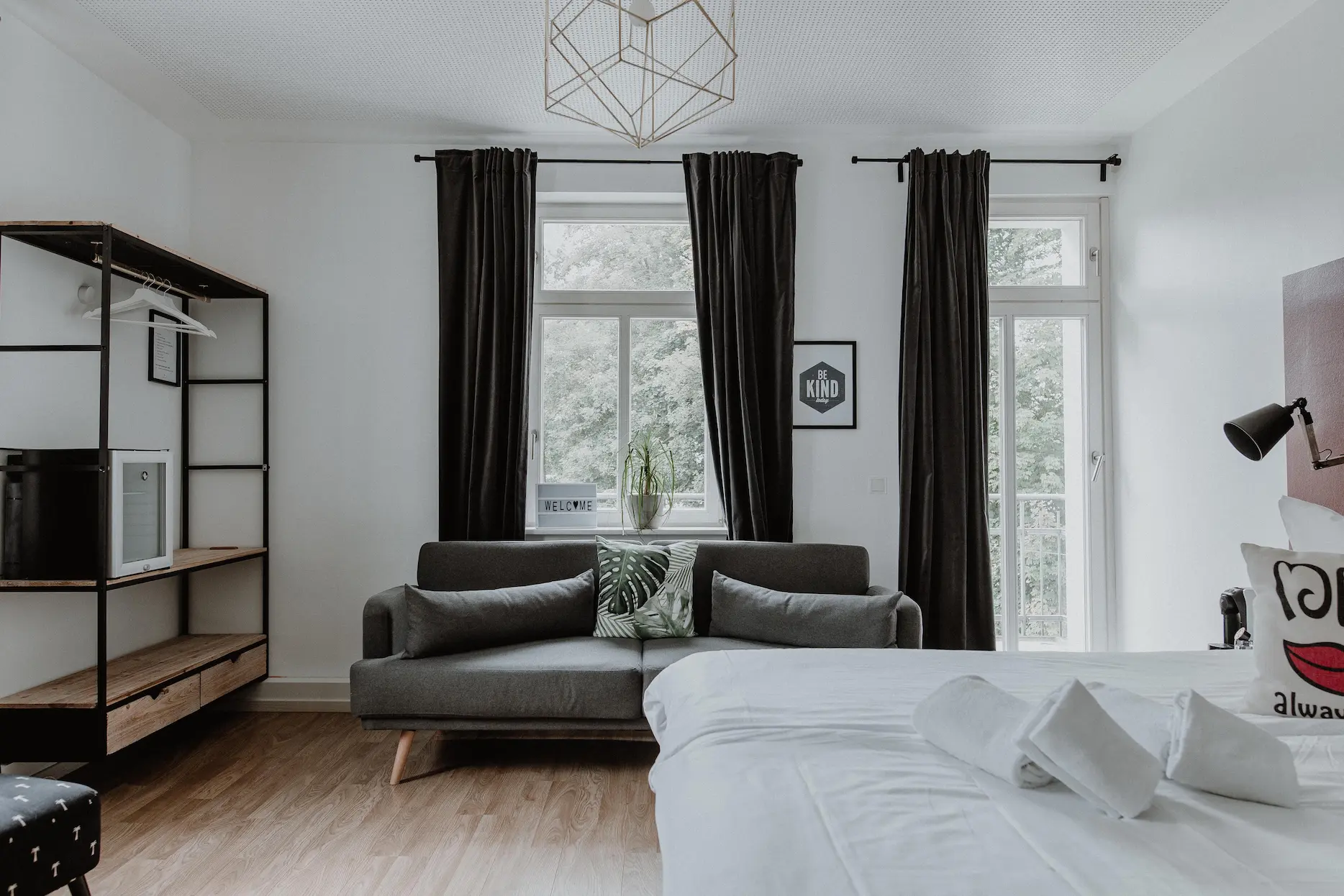 Zimmer Small mit Sofa, Minibar-Regal und Fenster zum Grünen im Boutiquehotel Palmenbad Kassel