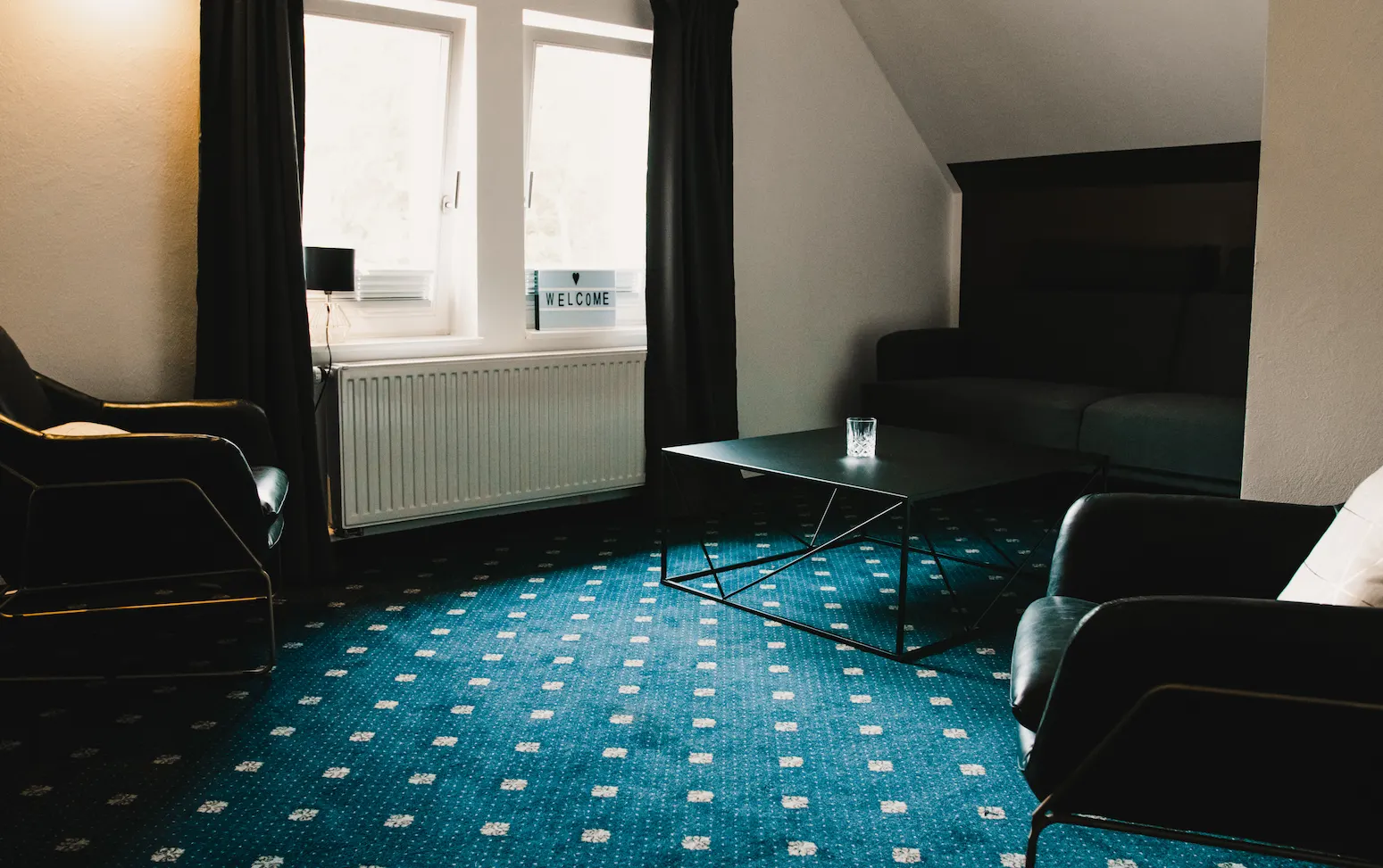 Suite Wohnbereich mit Ledersesseln und Welcome-Schild im Boutiquehotel Palmenbad Kassel