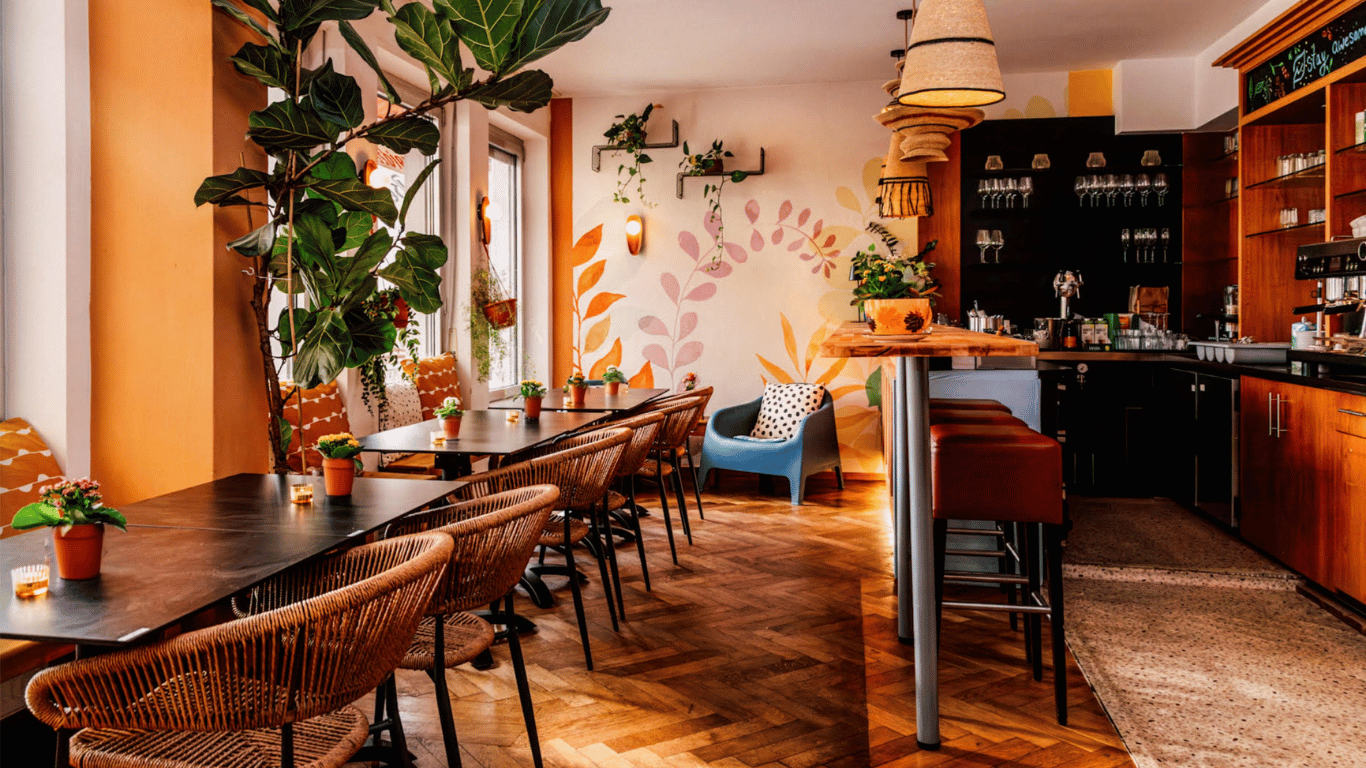 Café und Bar mit Pflanzen, Rattanstühlen und Holzboden im Hotel Kleiner Markt Saarlouis