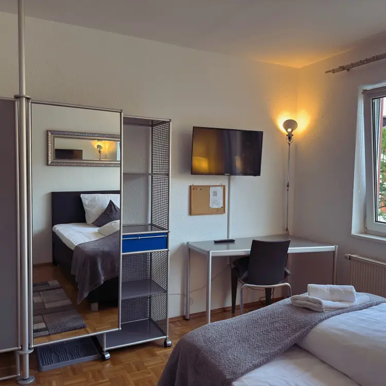 Studio im Boardinghaus Kassel mit Schreibtisch, TV, Spiegelregal und Handtüchern auf dem Bett