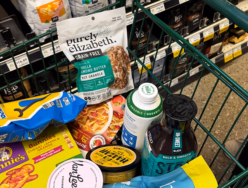 Grocery cart filled with products including Purely Elizabeth granola and bottled cold brew coffee