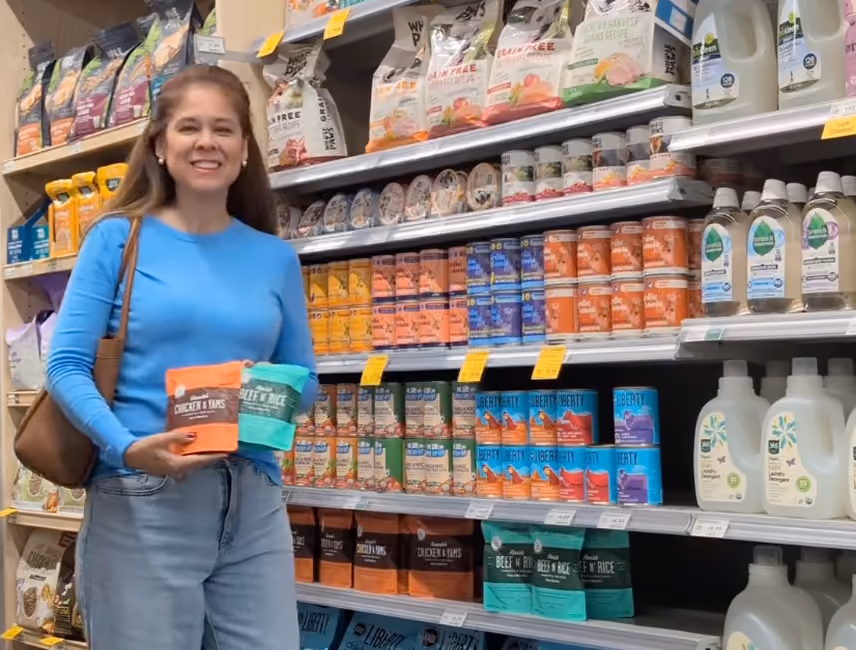 Woman in a pet food aisle holding Portland Pet Food Company pouches.