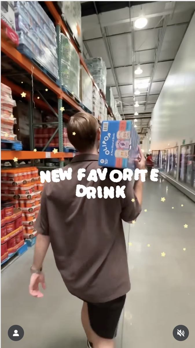 Creator carrying an OLIPOP pack through a Costco aisle