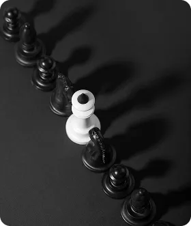 A white chess king piece surrounded by black pawns on a dark surface casting shadows.