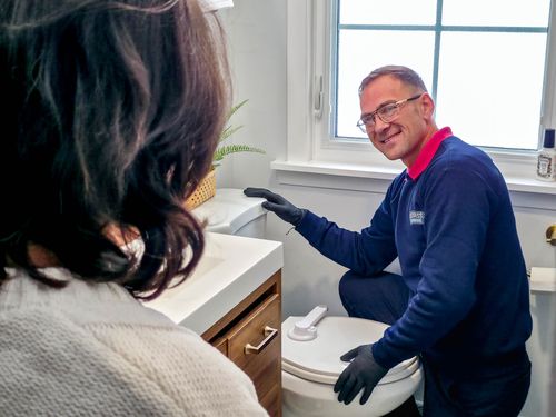 YesXpress Plumbing owner Valentin Varvaroi smiles while walking a Northbrook Illinois homeowner through a toilet repair.