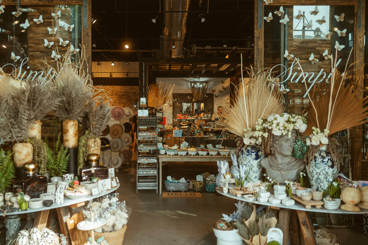 Interior of a rustic boutique shop displaying decorative vases with dried plants, ceramics, and various artisanal items.