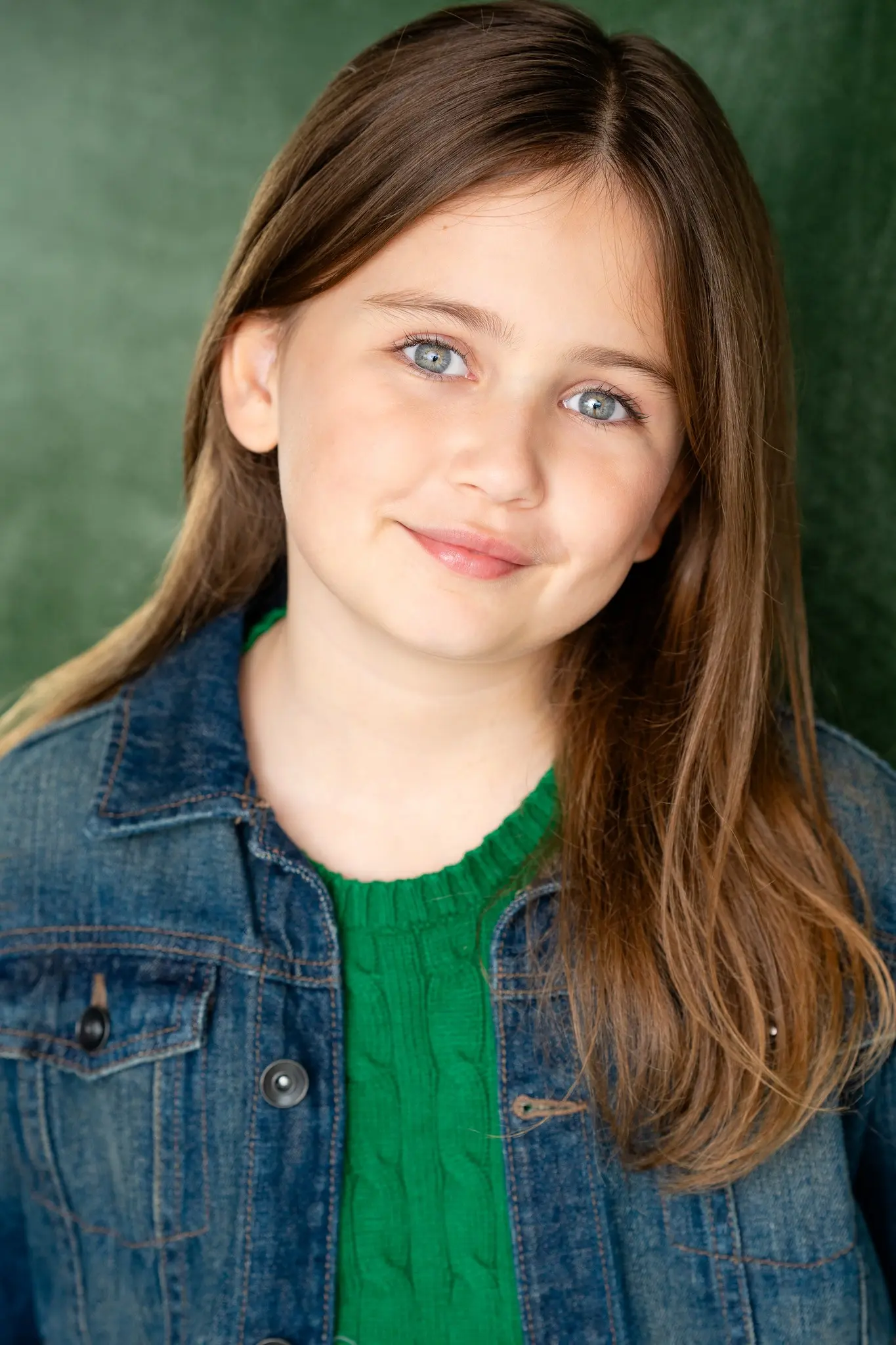 Caroline Brauner portrait headshot wearing denim jacket against green background