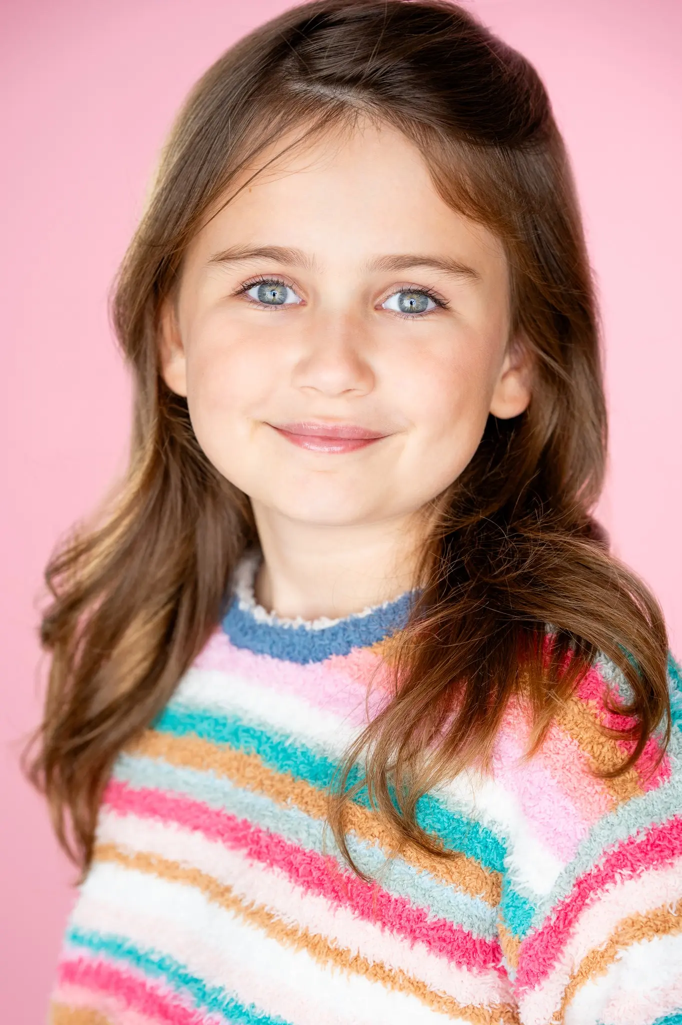 Caroline Brauner close-up portrait against pink background wearing striped sweater
