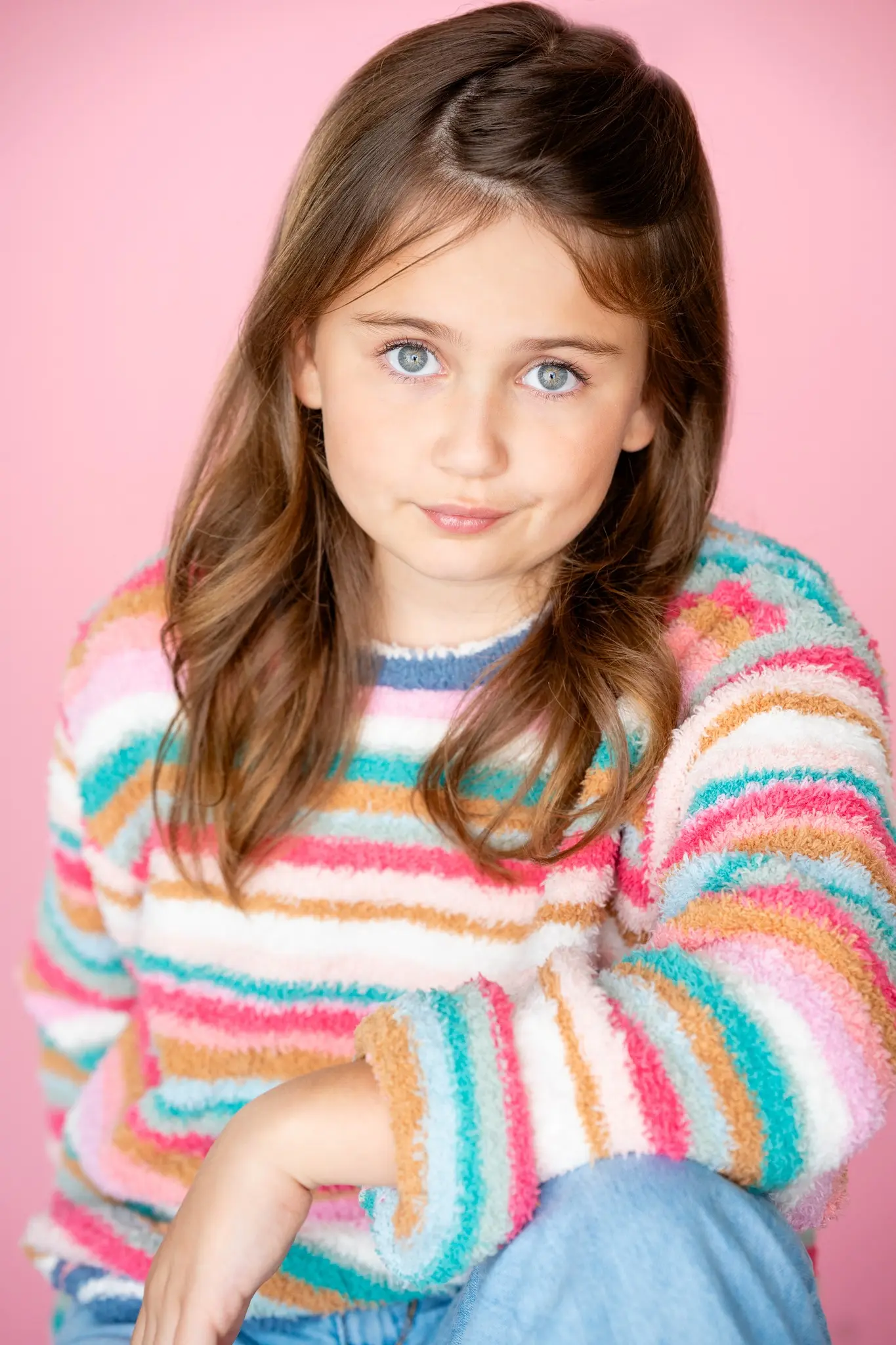 Caroline Brauner studio portrait against pink background wearing striped sweater