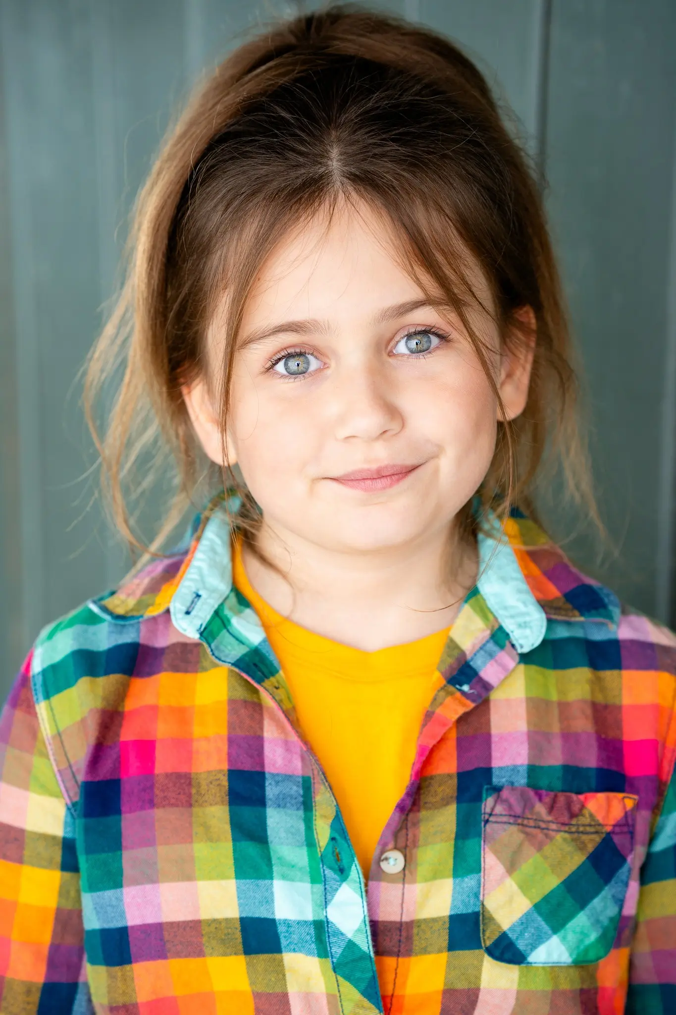 Caroline Brauner casual portrait wearing plaid shirt and yellow top with subtle smile