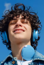 Person using a vacuum cleaner to clean office carpet near desks and chairs.