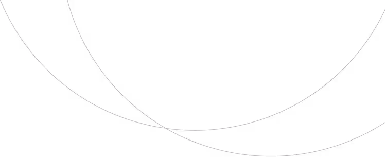 Dirt road curving through golden wheat fields with wind turbines and green trees under a blue sky.