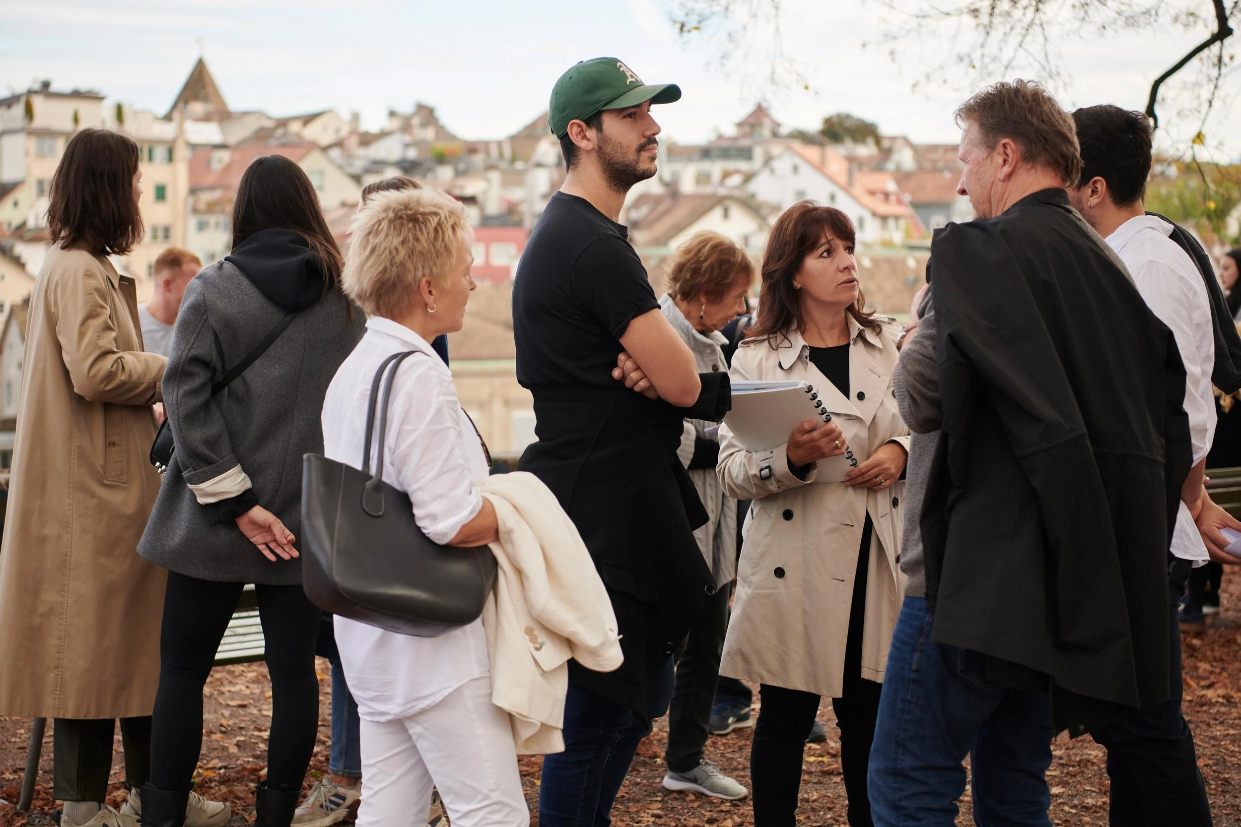 Group of people engaging in conversation outdoors with historic buildings in the background.