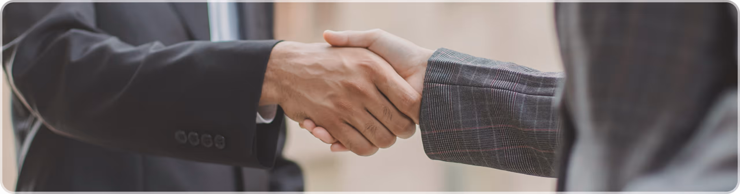 Two people in business attire shaking hands in a professional setting.