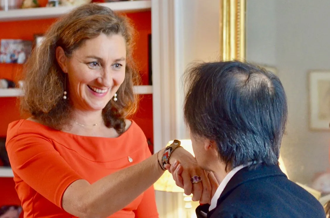 France de Heere supervisant l'apprentissage du baise-main par un homme lors d'un atelier sur la courtoisie française et l'élégance relationnelle.