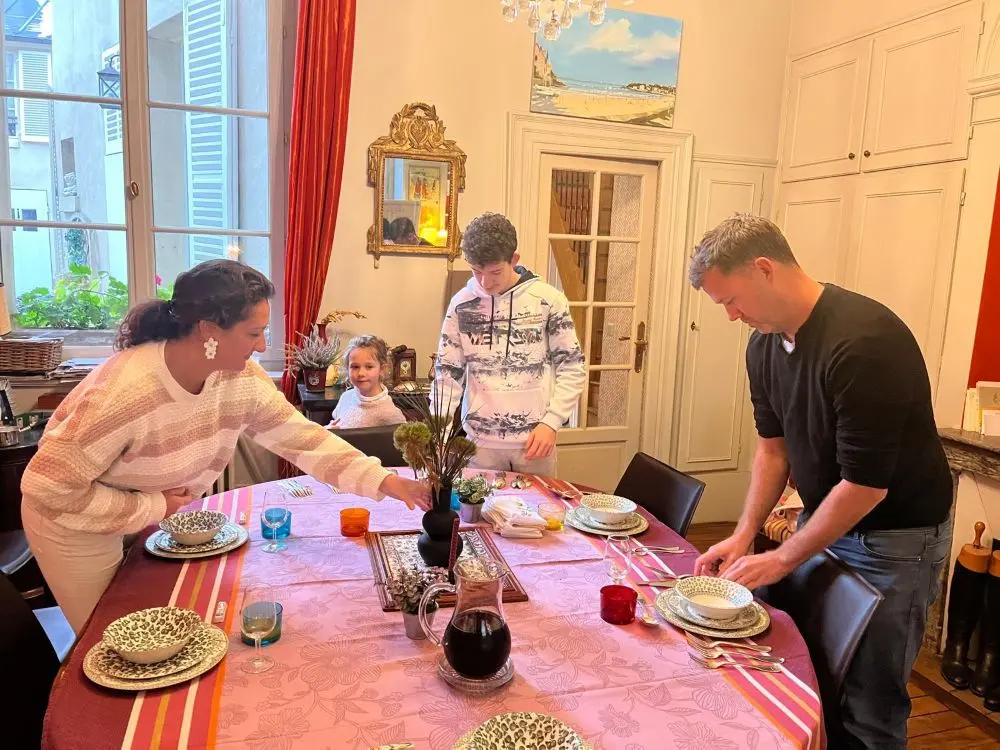 Une famille, avec un père et ses enfants, participant à un atelier interactif de France de Heere pour apprendre l'art de dresser une table élégante en famille.