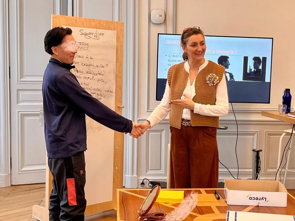 France de Heere serrant la main d'un jeune homme lors d'un atelier sur les présentations orales avec l'association Les Cordées de la Réussite, dans une salle de réunion.