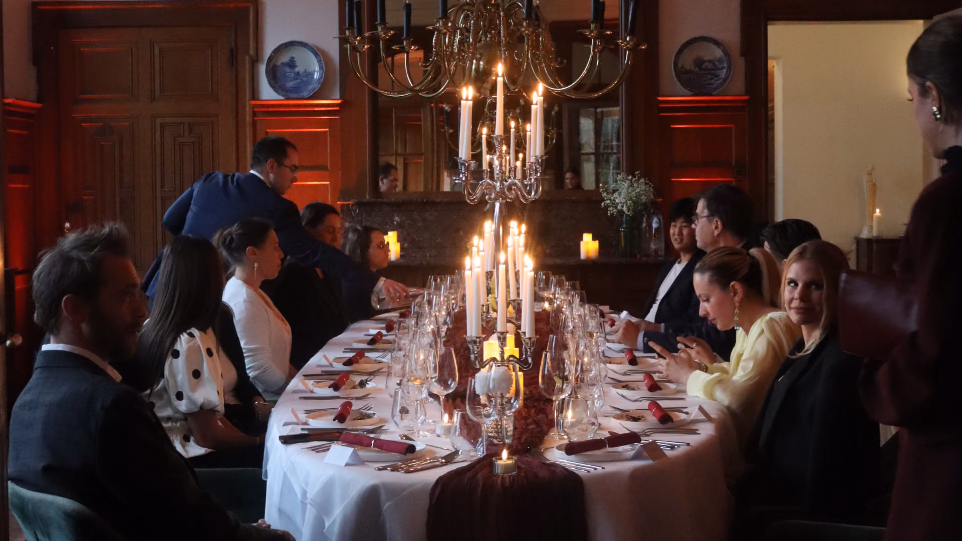 Close-up of a formally set dining table with multiple empty wine glasses, silverware, and folded white napkins on a white tablecloth.