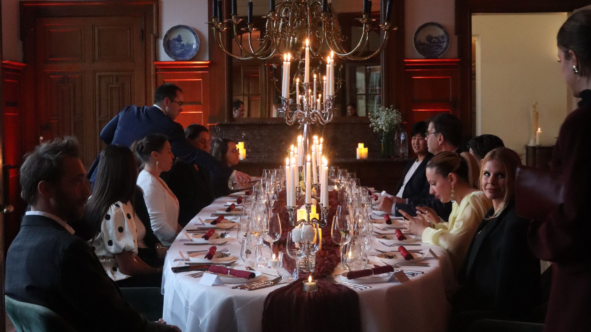Close-up of a formally set dining table with multiple empty wine glasses, silverware, and folded white napkins on a white tablecloth.