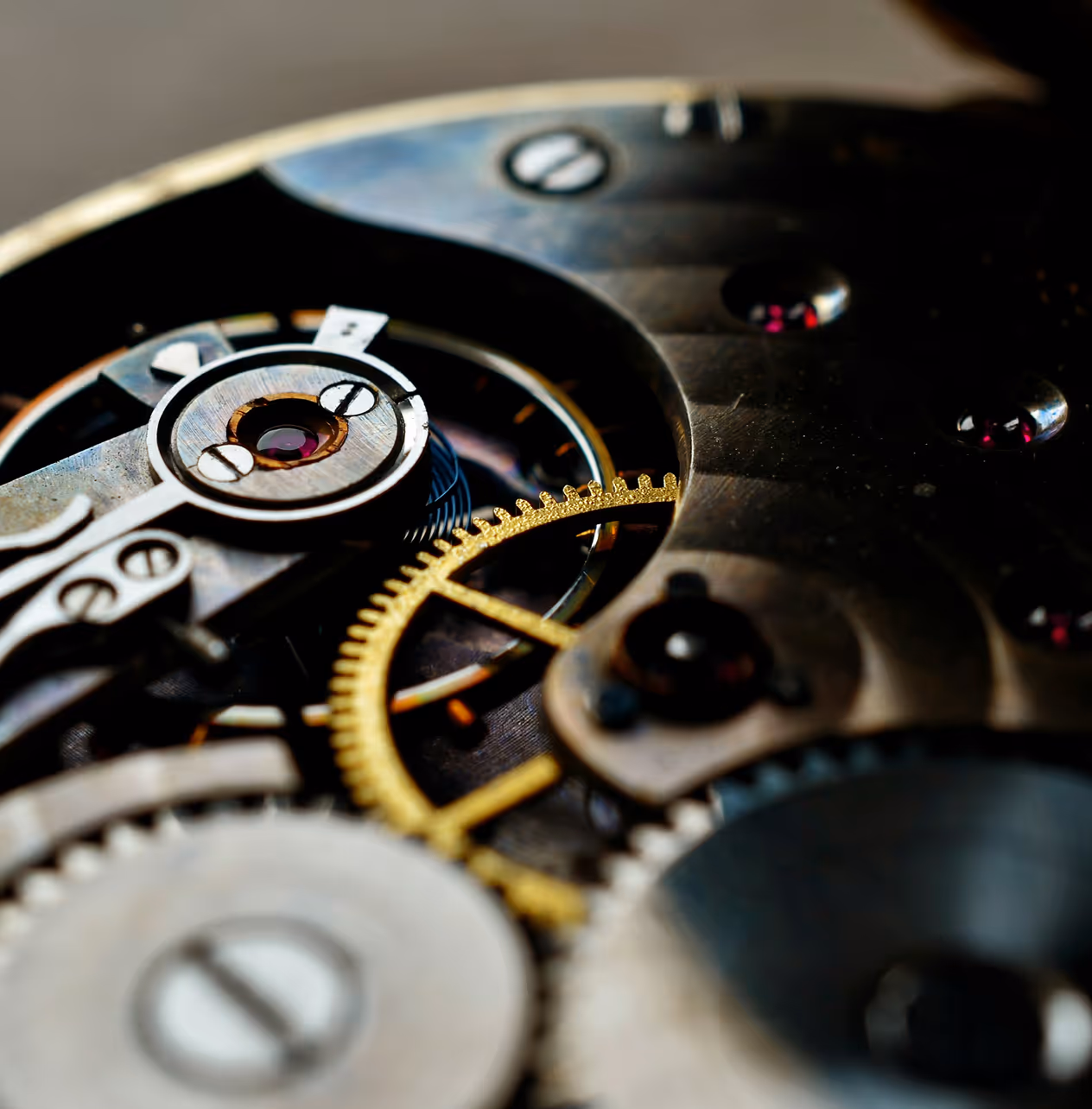 Gros plan sur les engrenages métalliques et dorés d'un mouvement de montre mécanique.