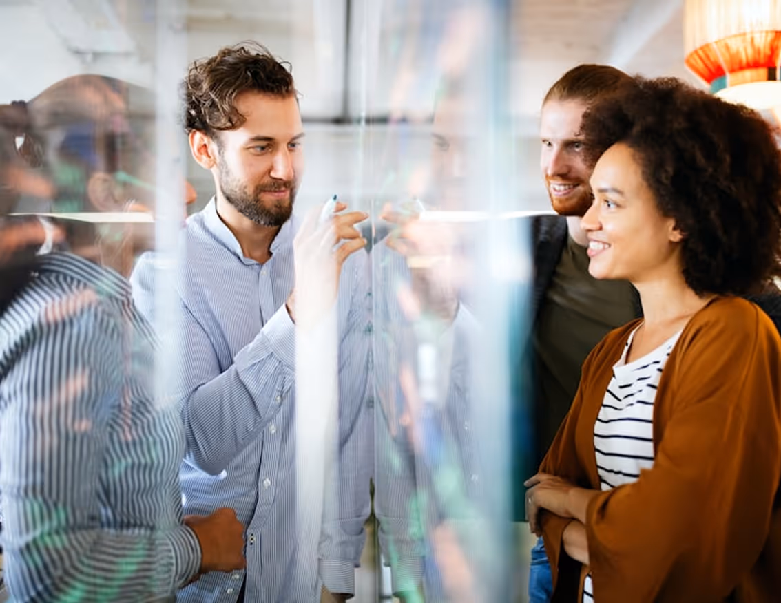 Une équipe de 4 personnes qui brainstorm sur un tableau