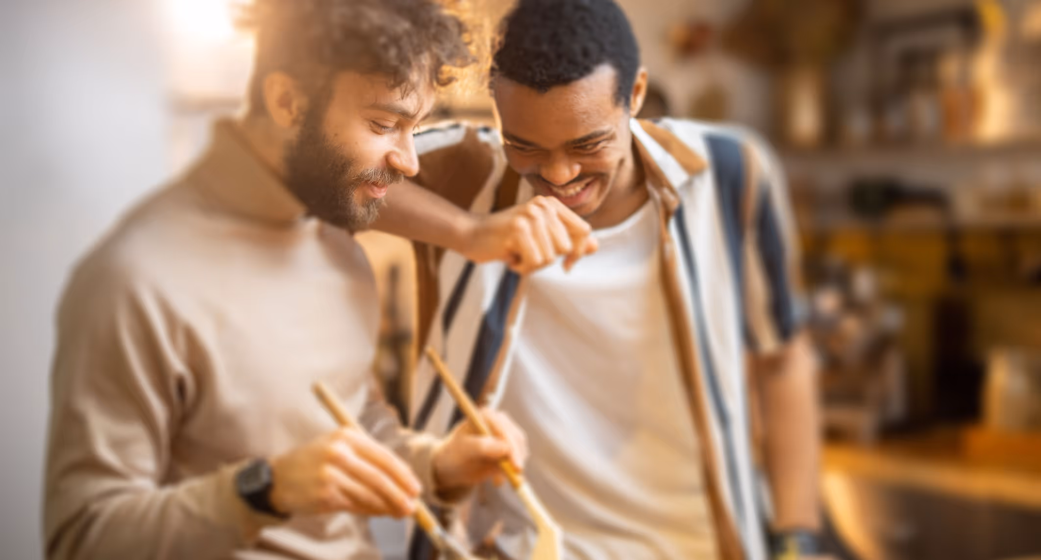 Two men smiling and painting together, focused on their work.