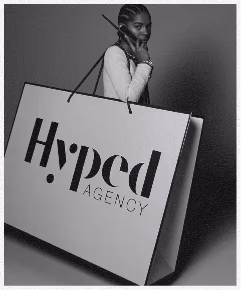 Une femme portant un sac géant affichant le logo de Hyped Agency, parlant au téléphone.
