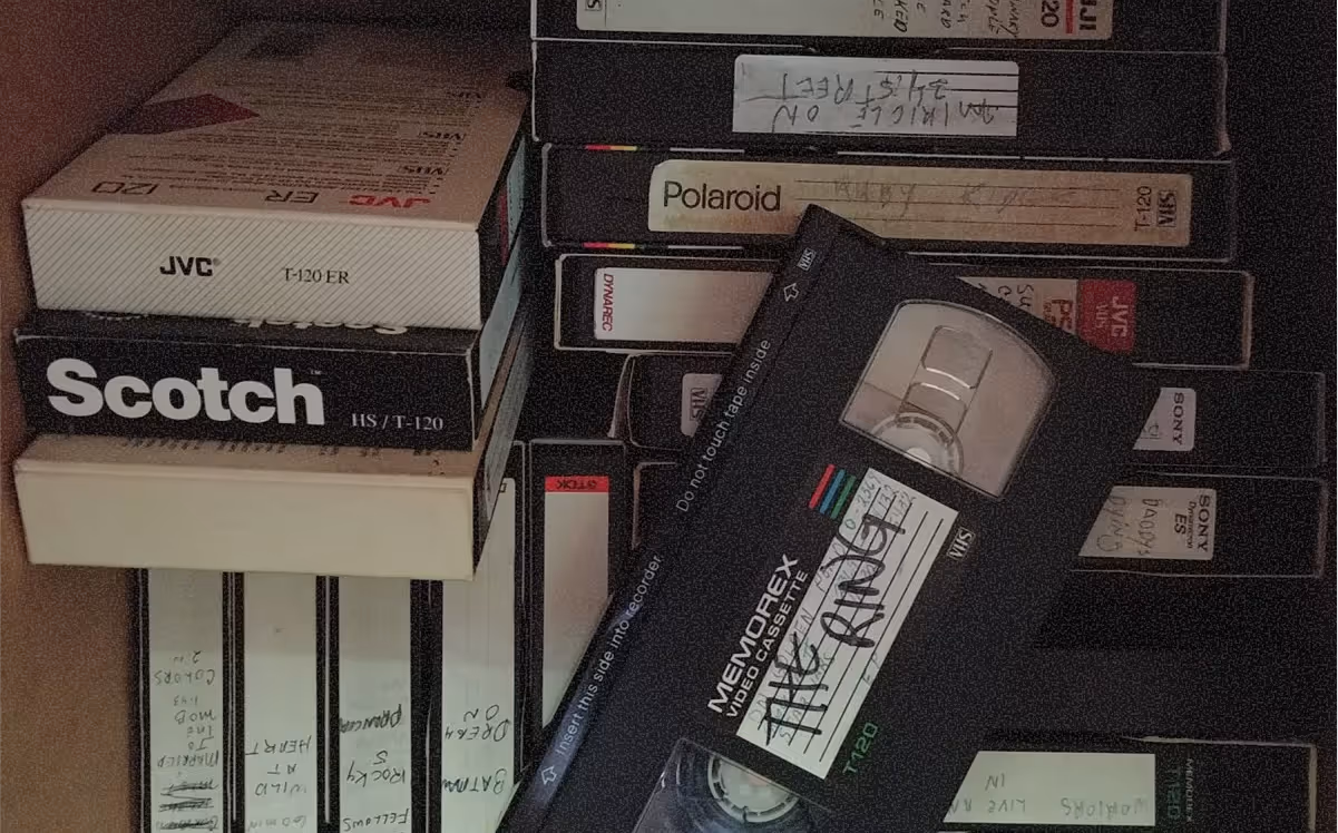 Pile de cassettes VHS de différentes marques avec une cassette Memorex noire au centre.