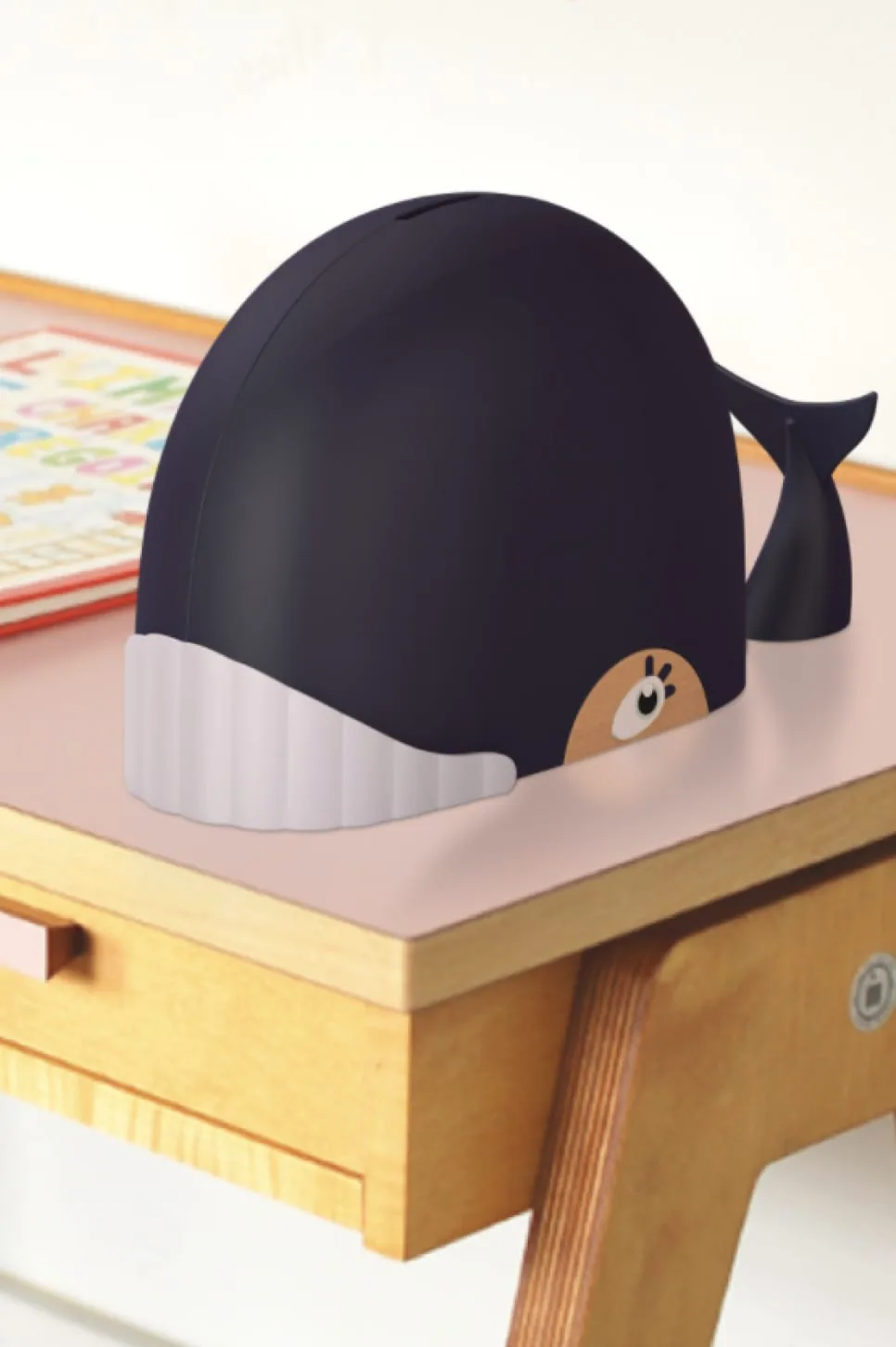 Tirelire connectée en forme de baleine noire posée sur une table en bois